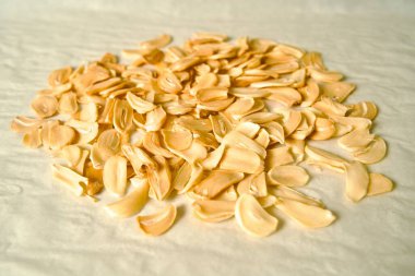 Chopped garlic slices gathered into a pile on baking paper clipart