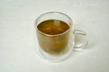 Şeffaf bir fincanda demlenmiş yeşil Pu-erh çayı, canlı rengini ve berraklığını sergiliyor..