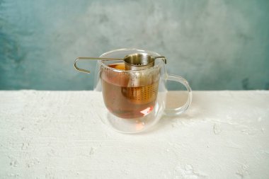 Şeffaf bardakta demlenmiş siyah Pu-erh çayı, zengin koyu rengini sergiliyor..