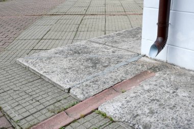 Binadan kaldırıma kadar temiz su çekmek için özel bir hendek, farklı fayanslar, fayansların eklemleri, atık su için metal borular.