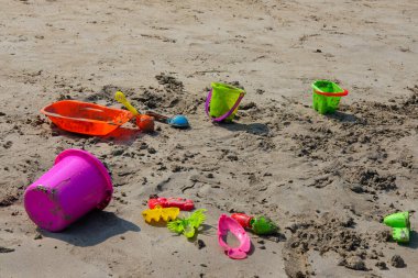 Kumsaldaki çocuklar için renkli plaj oyuncakları, kova, kale, tırmık ve kürek..