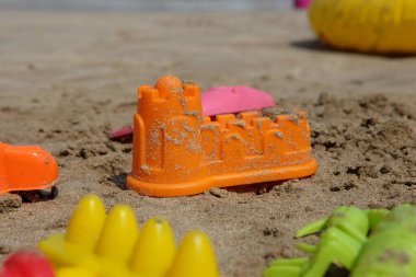 Bokeh manzaralı renkli plaj oyuncakları, kale tırmığı ve kumsaldaki çocuklar için kürek..