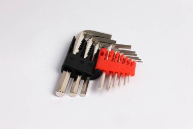 Plastik kutunun içindeki metal Allen anahtar ekipmanı beyaz arka planda izole edilmiş. Kırmızı alet kutusuna konmuş altıgen anahtarın metrik ölçekli ve asılmak için deliği olan görüntüsü. Çeşitli boyutlarda çelik cıvata el aletleri.