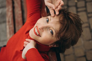 Parlak mavi gözleri ve parlak bir gülümsemesi olan neşeli bir kadın, canlı kırmızı bir kazak giymiş, açık havada poz veriyor. Rahatlamış, tasasız ifadesi sıcaklığı ve mutluluğu yayıyor. Yaşam tarzı, moda ve sağlıkla ilgili konular için mükemmel.. 