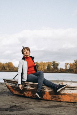 Bu fotoğraf kıyı şeridi boyunca eski, yıpranmış bir teknede oturan bir kadını gösteriyor. Manzaranın sıcacık, dünyevi tonları, resmin rahat ve maceraperest havasını arttırarak, günlük tarzını tamamlıyor..