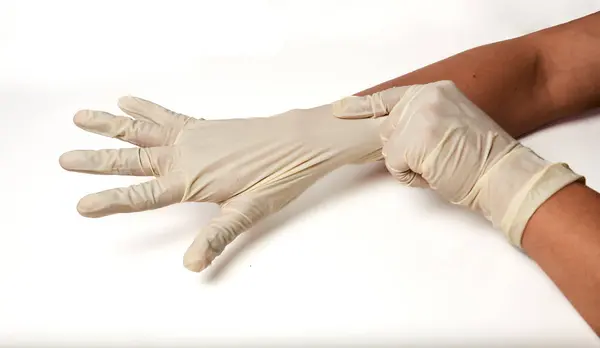 Latin bir doktor beyaz arka planda tıbbi eldiven giyiyor. Uzayı kopyala Ulusal Doktorlar Günü. Uluslararası Hemşireler Günü. Sağlık koruma ekipmanları.