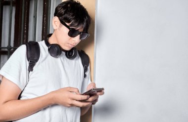 Kulaklıkla duvara yaslanırken mesajlaşan genç adam