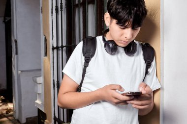 Boynunda kulaklıkla akıllı telefon kullanan genç adam. 