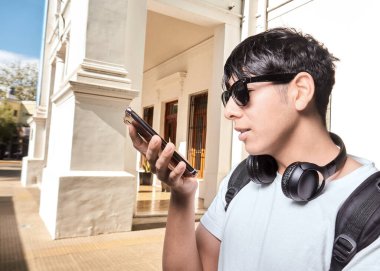 Genç adam akıllı telefonda ses asistanı kullanıyor.