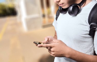 Açık havada akıllı telefon kullanan genç adamın elleri.