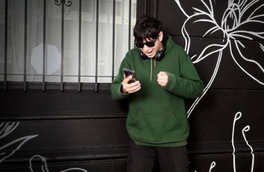 Genç adam telefonundan iyi haberi kutluyor.