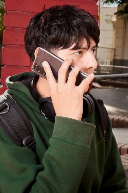 Telefonda Kırmızı Tuğla Duvarı 'nın yanında konuşan genç çocuk. 