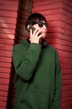 Genç çocuk telefonda konuşurken gülümsüyor. 