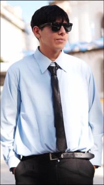  Güneş gözlüklü genç adam şehir caddesinde akıllı telefonu kontrol ediyor.