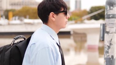  Sırt çantasıyla Nehir kenarında yürüyen genç adamın yan görüntüsü