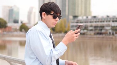 Şehir Nehir Kenarı Ayarlarında Genç Adam Akıllı Telefonu Tutuyor