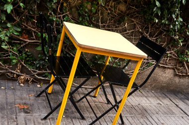 Yapraklı Şehir Merkezinde Siyah Sandalyeli Sarı Açık Masa