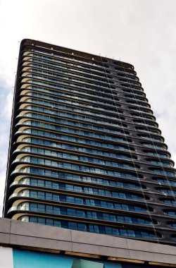 Yansıtıcı Pencereleri ve Yuvarlak Balkonları olan Modern Eğri Cam Kule