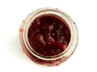 Açık cam bir kavanozda çilek reçeli. Beyaz arka planda izole edilmiş kalın meyve koruma ve ev yapımı tatlı kahvaltı konsepti ve yiyecek deposu.