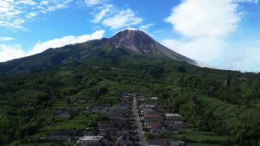 Drone Video: Merapi Dağı 'nın eteğindeki bir köyün güzelliği. Bu fotoğraf Merapi Dağı eteğindeki bir köyün çarpıcı manzarasını sergiliyor. Beyaz bulutlu berrak gökyüzü bu köyün güzelliğini ve huzurunu artırıyor..