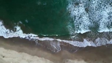 Sanatsal hava görüntüsü kumlu bir sahile çarpan büyük dalgaların Sawarna Sahili, Banten, Endonezya 'da ilginç desenler oluşturduğunu gösteriyor..