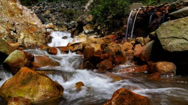 Bambudan akan sıcak su, Endonezya 'nın Bogor kentindeki Halimun Dağı Ulusal Parkı ormanının ortasında yer alan şelaleden gelen soğuk su nehriyle birleşir..