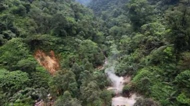 İnsansız hava aracı Endonezya 'nın Bogor şehrindeki Halimun Dağı Ulusal Parkı' nda uçuyor. Gerçek zamanlı olarak ilerliyorum. Kraterin dumanından, temiz nehir akışından ve yoğun yeşil ormandan görüldü..
