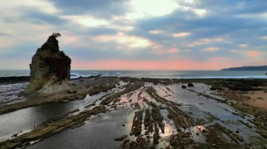 Gün batımına doğru havadan görüntü hareketi. Tanjung Layar Sawarna Sahili, Banten, Endonezya 'da ikonik bir turizm merkezi. Tekne yelkeni şeklinde metamorfik çökeltilerden oluşan kayalar..