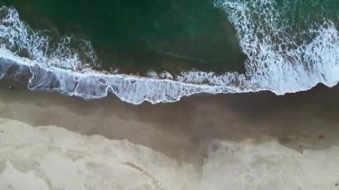 Sanatsal hava görüntüsü kumlu bir sahile çarpan büyük dalgaların Sawarna Sahili, Banten, Endonezya 'da ilginç desenler oluşturduğunu gösteriyor..