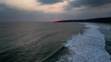 Sawarna Sahili, Banten, Endonezya 'da günbatımında geriye doğru hareket eden insansız hava aracı. Dalgalar birbirini kovalarken güzel görünüyor..