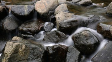 Büyük kayalar akarsu boyunca dağılır, üzerlerinde yumuşak su akar, sakinleştirici doğal bir manzara yaratır. Uzun Pozlandırma