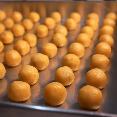 Nastar cookies with pineapple jam and shiny orange egg yolk spread, neatly arranged on an aluminum tray, ready to be cooked. This traditional Indonesian food is served during Eid al-Fitr celebrations. clipart