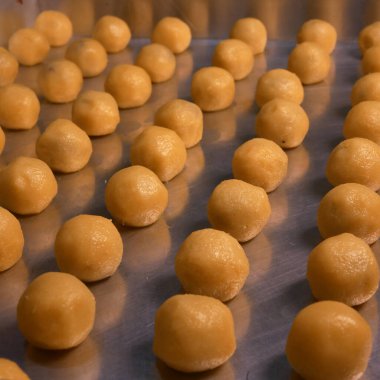 Nastar cookies with pineapple jam and shiny orange egg yolk spread, neatly arranged on an aluminum tray, ready to be cooked. This traditional Indonesian food is served during Eid al-Fitr celebrations. clipart