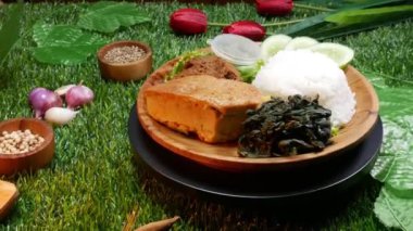 Padang, Endonezya 'dan geleneksel Padang Rice yemeklerini, içinde beyaz pirinç, sığır eti rendang, omlet, dilimlenmiş salatalık, yeşil biber sosu ve meyveli sebze bulunan ahşap bir tabakta kapayın..