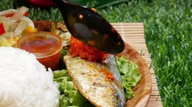 Beyaz pirinçli tam bir yemek, kırmızı samballı kızarmış balık, kızarmış tempeh, kızarmış tofu, taze sebze, sambal ve salatalık dilimleri..