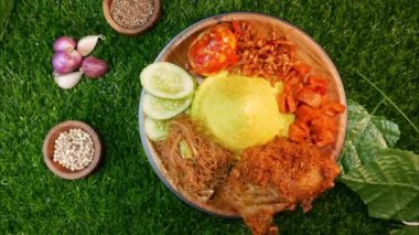 Top View A servis koni şeklinde tavuk, kızarmış vermicelli, sambal, salatalık dilimleri, sambal yumurta ve kırmızı soğan ve biber gibi baharatlarla eşleştirilmiş sarı pirinç..