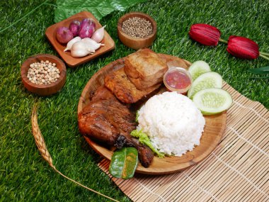 Nasi Campur is a traditional Indonesian food, consisting of white rice, grilled chicken, tofu, tempeh, chili sauce, and fresh cucumber, on a wooden plate on a synthetic grass base. clipart