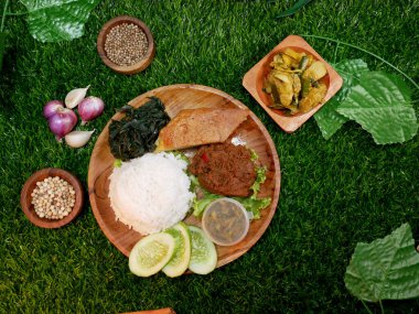 Top View Nasi Padang, Endonezya 'dan tamamen geleneksel bir yemektir, içinde beyaz pirinç, sığır eti rendang, omlet, dilimlenmiş salatalık, yeşil biber sosu ve meyveli sebze vardır..