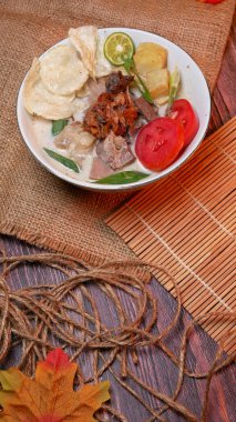 Soto Betawi ve sığır eti, patates, taze domates, limon dilimleri ve kızarmış soğan. Benzersiz bir dekorasyonla beyaz kasede servis edilmiş. Kullanılabilir metin için boşluk