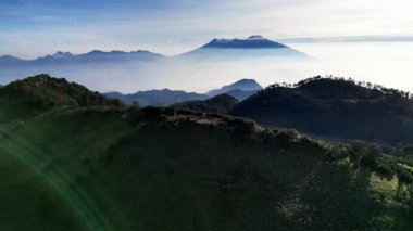 Butak Dağı 'nın zirvesindeki dramatik sabah manzarası. Arka plan Arjuno Welirang volkanı sabah sisinde örtülü..