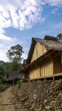 Endonezya 'nın Banten kasabasındaki Baduy Kabilesi' nin dışındaki açık hava bulutlu mavi gökyüzü ve geleneksel yapışkan evleri ormanın ortasında sessiz ve huzurlu bir köy gösteriyor..