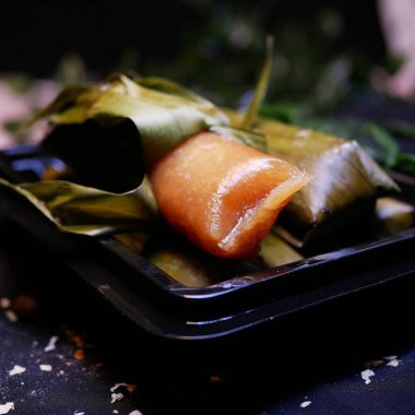 Tatlı Cassava Ketimus 'un yakın çekimi, kısmen açık ve altın rengi kahverengi ve diğeri hala muz yaprağına sarılı, geleneksel bir Endonezya yemeği, öğleden sonra sıcak çayla servis ediliyor..