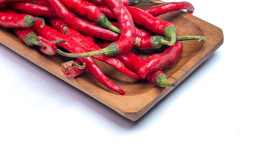 Taze kıvırcık kırmızı biberli yeşil saplı ahşap tepside beyaz arka planda izole edilmiş.