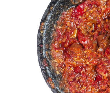 Beyaz zemin üzerinde izole edilmiş, taş bir havanda kırmızı biber ve soğandan yapılan Endonezya baharatlı toprak sambal üst görünümü