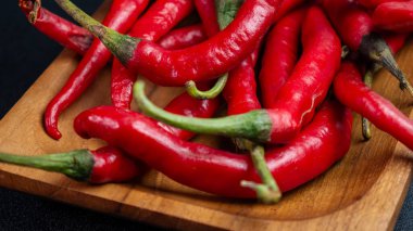 Ahşap tepside taze yeşil saplı kırmızı biberli yakın çekim. Yemek pişirmeye ya da yemek pişirmeye uygun.