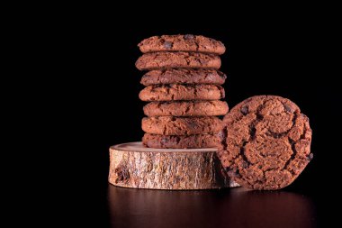 Ev yapımı çikolatalı kurabiyeler. Odaklanmış ışık ve koyu siyah arkaplan ile ahşap bir zemine yerleştirilmiş. Reklam ve promosyon için mükemmel..