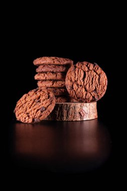 Odaklanmış ışık ve koyu siyah arkaplanı olan ahşap bir zemine yerleştirilmiş çikolatalı kurabiyeler. Reklam ve promosyon için mükemmel..