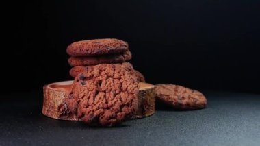 Tahtanın üzerinde koyu arkaplanlı çıtır çikolatalı kurabiyeler dönüyor. Gıda ürünlerinin reklamı veya tanıtımı için mükemmel..