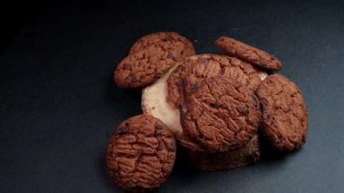 Yavaş çekimde dönen siyah arka planlı gevrek çikolatalı kurabiyeler. Gıda ürünleri reklamı veya tanıtımı için mükemmel..