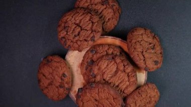 Tahta ayakta gevrek çikolatalı kurabiyelerin ve siyah pikabın yavaş çekim üst görüntüsü. Yemek reklamı için mükemmel..